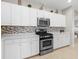 White cabinets, stainless steel appliances and mosaic backsplash at 4831 Boston Common Gln, Bradenton, FL 34211