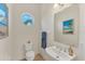 Small powder room with white vanity, toilet, and decorative mirror at 634 Key Royale Dr, Holmes Beach, FL 34217