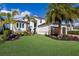 Stunning white home with a lush green lawn and beautiful tropical landscaping at 696 Regatta Way, Bradenton, FL 34208