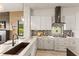 Modern kitchen with white cabinets, mosaic backsplash, and a farmhouse sink at 696 Regatta Way, Bradenton, FL 34208