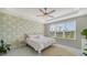 Sunlit bedroom features a ceiling fan, green leafy wallpaper, and a scenic view from the window at 10109 Milky Way Cir, Sarasota, FL 34241