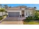 One-story home with gray garage doors, paver driveway, and lush landscaping at 10201 Beach Dune Dr, Englewood, FL 34223