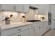 White kitchen with gas cooktop, quartz countertops, and stylish backsplash at 10201 Beach Dune Dr, Englewood, FL 34223