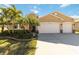 Three-car garage tan house with palm trees and manicured lawn at 14822 Trinity Fall Way, Bradenton, FL 34212