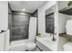 Modern bathroom with dark gray tile, white vanity, and a shower/tub combo at 3822 75Th E Ter, Sarasota, FL 34243