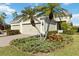 Two-car garage, light beige house with lush landscaping and palm trees at 4891 Maymont Park Cir, Bradenton, FL 34203