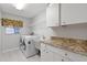 Bright laundry room with built-in cabinets, granite countertops, and a utility sink at 5061 Seagrass Dr, Venice, FL 34293