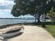 Scenic waterfront pathway with benches and a boat under a large tree at 531 N Spoonbill Dr, Sarasota, FL 34236