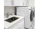 Laundry room with white cabinets, stainless steel sink, and washer/dryer at 5337 Popoli Way, Sarasota, FL 34238