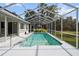 Screened-in pool area with surrounding grassy yard at 5574 Sweetwater Oak, Sarasota, FL 34232