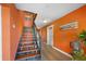 Stylish staircase featuring wood steps, steel supports, and vibrant orange wall with decorative artwork at 614 Norton St, Longboat Key, FL 34228