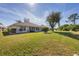 Back exterior view showcasing a house with a large grassy yard at 8240 Parkside Dr, Englewood, FL 34224