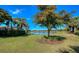 Beautiful backyard view with a serene lake, lush greenery, and palm trees against a clear blue sky at 8279 Varenna Dr, Sarasota, FL 34231