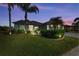 Well-lit home at dusk with lush landscaping and palm trees at 12904 49Th E Ln, Parrish, FL 34219