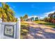 Light blue house with metal roof, paver driveway, and tropical landscaping at 1649 Manor Rd, Englewood, FL 34223