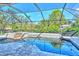 Screened-in pool with a spa, waterfall feature, and views of the water and mature trees at 1705 Shoreland Dr, Sarasota, FL 34239