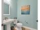 Powder room with pedestal sink, toilet, and beach-themed art at 17722 Littleton Pl, Lakewood Ranch, FL 34202