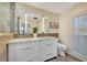 Bright bathroom featuring double vanity with white cabinets, a large mirror, and decorative tile accents at 320 Avenida Leona, Sarasota, FL 34242