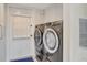 Bright laundry room with modern washer and dryer, white cabinets, and a door to the exterior at 320 Avenida Leona, Sarasota, FL 34242