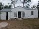 White house with gray roof, open garage doors, and small front yard at 3218 Avenue A W, Bradenton, FL 34205