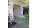 Home exterior featuring neutral tones, a tiled entryway, and a glimpse of the front door beyond lush foliage at 4108 Carriage Way # 6, Sarasota, FL 34241