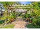 Brick patio with wooden pergola covered in lush vines and benches, creating a relaxing outdoor space at 4563 Trails Dr, Sarasota, FL 34232