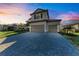 Two-story house with gray siding, tile roof, and a paved driveway at sunset at 4852 Coastal Days Ln, Bradenton, FL 34211