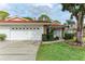 White stucco home with a red tile roof, two-car garage, and landscaped yard at 5613 Garden Lakes Dr, Bradenton, FL 34203