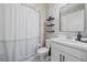 Bright bathroom featuring a white vanity, framed mirror, black floating shelves and a shower with a striped curtain at 6347 Grandview Hill Ct, Bradenton, FL 34203