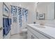 Clean bathroom with blue-themed decor featuring a framed mirror and a shower with a blue leaf shower curtain at 6347 Grandview Hill Ct, Bradenton, FL 34203