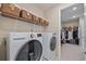 Well-organized laundry room featuring washer/dryer with overhead shelving and baskets and a view into a large walk-in closet at 6347 Grandview Hill Ct, Bradenton, FL 34203