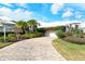 House exterior featuring a brick driveway, lush landscaping, and a two-car garage at 6790 Paseo Castille, Sarasota, FL 34238