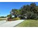 Entrance to the Fairway Lakes community featuring an American flag, mature trees, and lush landscaping at 7412 Links Ct, Sarasota, FL 34243