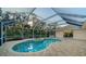 Screened-in pool features a jacuzzi, lounge chairs, and brick paver deck with a view of a lush green tree line at 7412 Links Ct, Sarasota, FL 34243