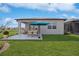 Back patio with dining furniture overlooks the landscaped backyard under a blue sky at 9405 Ballaster Pointe Loop, Parrish, FL 34219