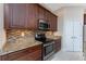 Close-up of the kitchen featuring dark cabinets, granite countertops, stainless steel appliances, and tiled backsplash at 1069 Harbour Cape Pl, Punta Gorda, FL 33983