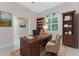 Bright office featuring a wooden desk, built-in shelves, and natural light from the arched window at 1069 Harbour Cape Pl, Punta Gorda, FL 33983