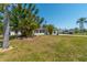 Ranch style home with a spacious front yard, lush landscaping, and palm trees at 134 Rotonda Cir, Rotonda West, FL 33947