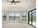 A bedroom with tray ceiling, large windows, natural light and views of the backyard at 14208 Woodhall Pl, Bradenton, FL 34202