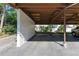 A covered carport area with a white textured wall and a view of the condo in the background at 3500 El Conquistador Pkwy # 119, Bradenton, FL 34210