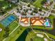 Aerial view showcasing tennis courts, pool, clubhouse, lush landscaping, and golf course fairways at 4705 Sand Trap Street E Cir # 105, Bradenton, FL 34203