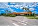 A well maintained exterior shot of a clubhouse featuring mature landscaping, palm trees, and ample parking at 4705 Sand Trap Street E Cir # 105, Bradenton, FL 34203