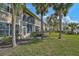 Back of condo featuring screened lanais, palm trees and grass lawn at 4705 Sand Trap Street E Cir # 105, Bradenton, FL 34203