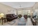 Cozy living room with leather sofa, ceiling fan, and sliding glass doors to the lanai at 4705 Sand Trap Street E Cir # 105, Bradenton, FL 34203