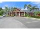 Exterior of the community clubhouse featuring red siding, a covered porch, and ample parking at 5711 Soldier Cir # 204, Sarasota, FL 34233