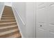 Carpeted staircase with white handrail leading to the upper level, complemented by a convenient closet at 5711 Soldier Cir # 204, Sarasota, FL 34233