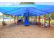 A kid walks in the Longwood Park playground with a shade and various play structures for children at 5827 Beaurivage Ave, Sarasota, FL 34243