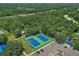 Overhead view of two well-maintained, blue and green tennis courts next to a parking area and surrounded by trees at 5827 Beaurivage Ave, Sarasota, FL 34243