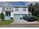 Two-story condo with teal accents, two-car garage, and a truck parked in the driveway at 6589 Fairway Gardens Dr, Bradenton, FL 34203