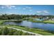 Scenic view of the community pool, walking path and lake, with lush landscaping and modern architecture on a sunny day at 8250 Velda Trl, Sarasota, FL 34241